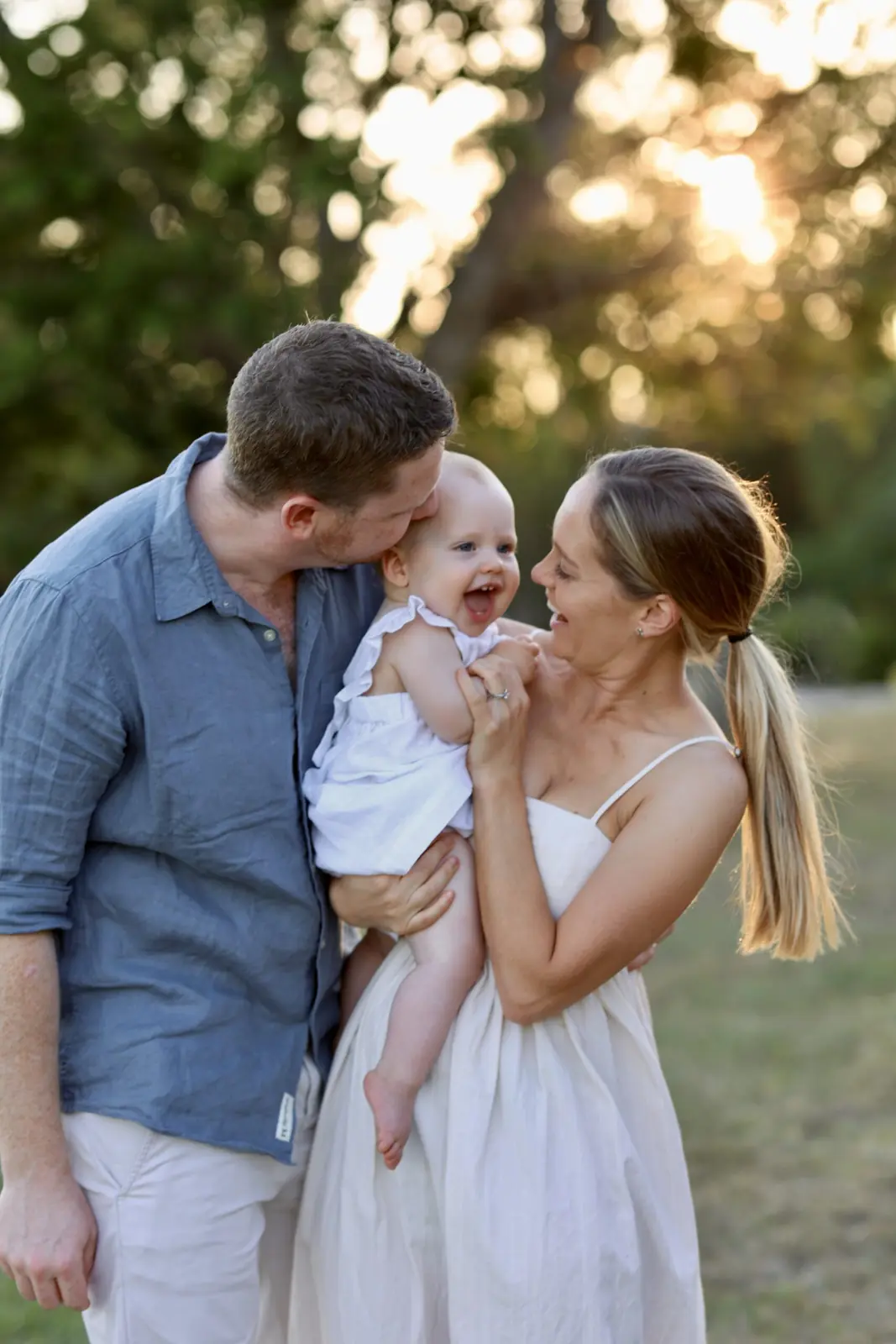 Parents laughing with their baby in golden evening light