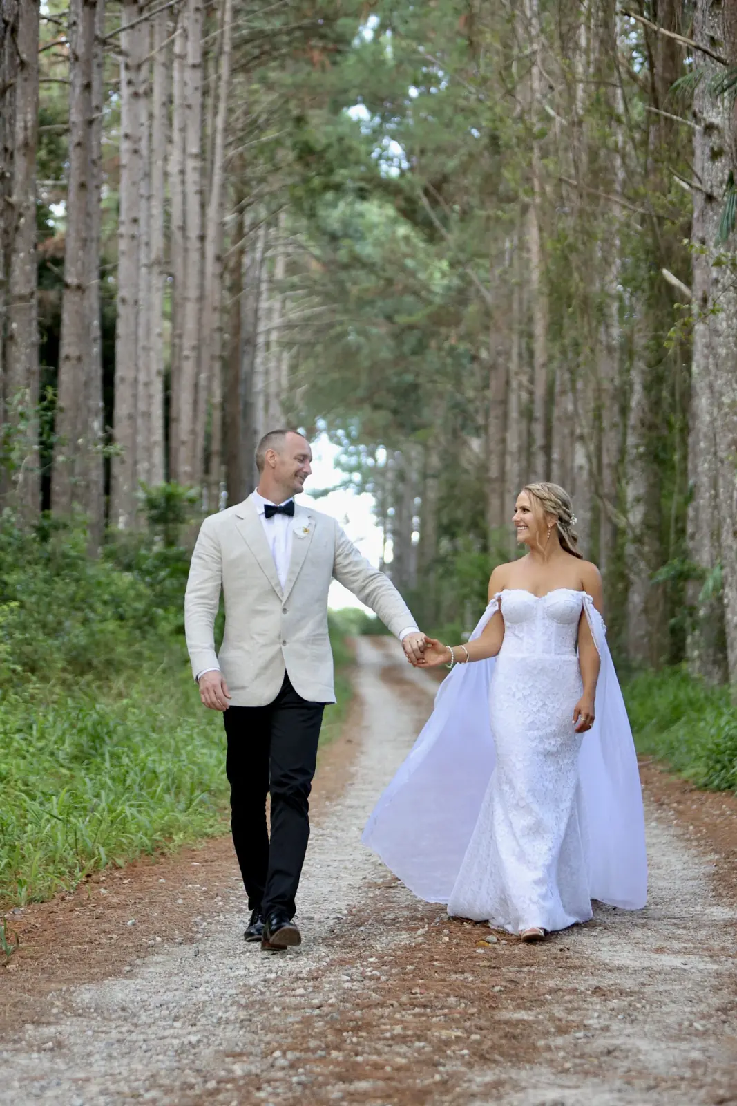 Bride and groom walking hand in hand along a forest path
