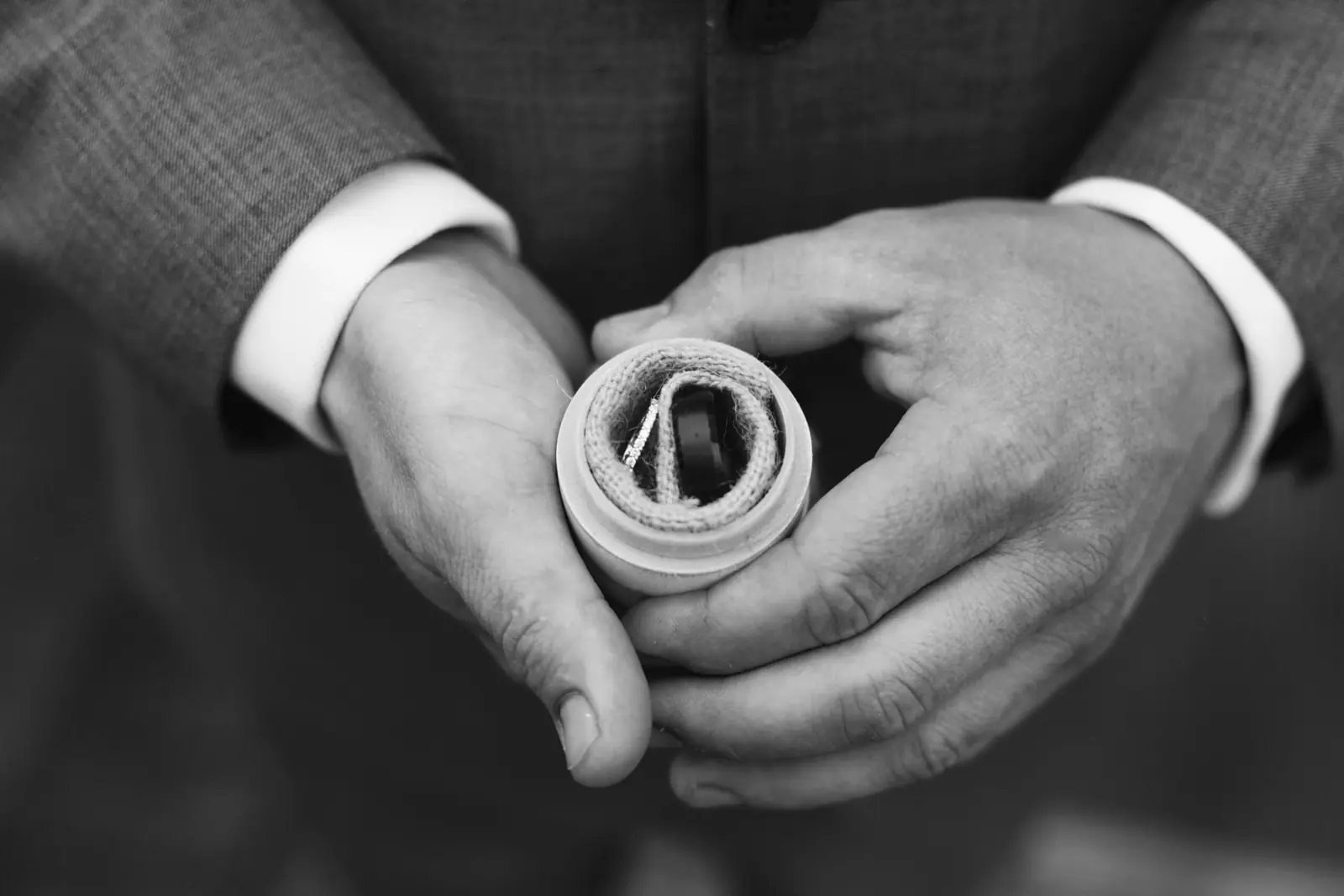 Black and white photo of hands holding a wedding ring